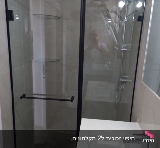 מקלחון פינתי מזכוכית עם פרופיל וצירים שחורים בחדר רחצה
